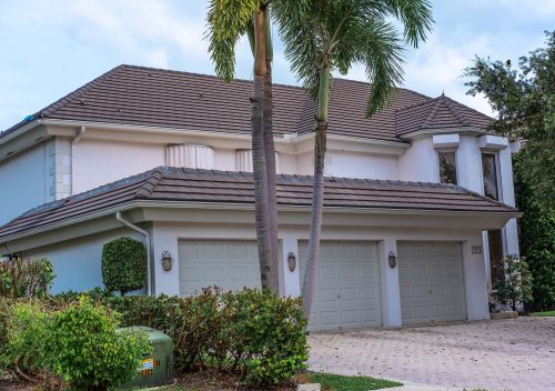 Hurricane Rolldown Shutters and Accordion Shutter on a Boca Raton home with white exterior paint and brown roof.